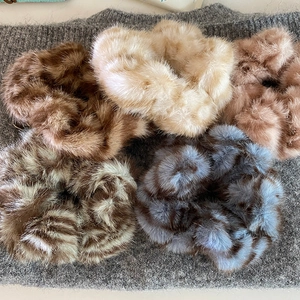 Plush leopard print scrunchies in five colors on a textured knit background