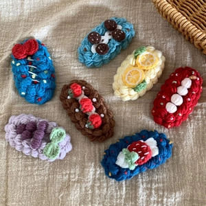 Détail de 7 barrettes à cheveux au crochet faites main avec motifs de fruits sur lin beige