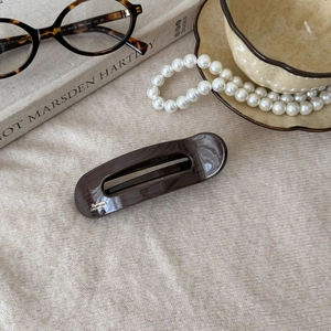 French retro acetate hair clip in dark tortoiseshell finish on beige knit background