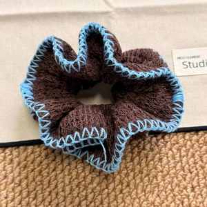 Close-up of knit scrunchie with brown wool texture and blue contrast edge stitching
