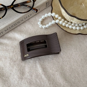 Detail of dark brown wood grain hair claw clip with golden Barrette La France logo