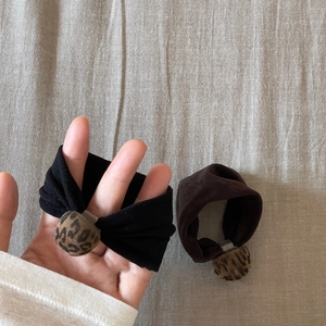 Detailed view of leopard print charm elastic hair ties in black and brown fabric