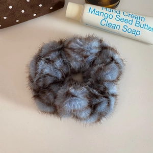 Close-up of fuzzy leopard print scrunchie in blue-grey and dark brown plush texture