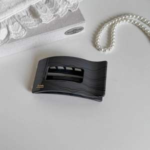 Detail of grey marble textured duckbill clip with gold branding on white background