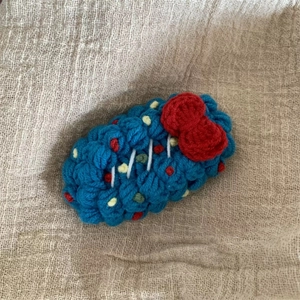 Détail de la barrette à cheveux au crochet faite main avec laine bleue et nœud rouge