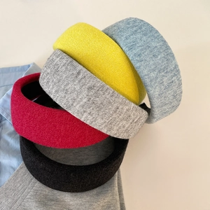 Five assorted colors of textured knit wide headbands for women shown in a layered stack