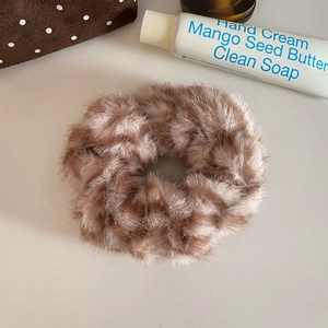 Close-up of plush faux fur hair scrunchie in light brown with soft texture detail
