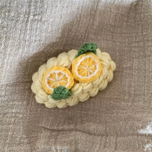 Détail d'une pince à cheveux au crochet faite main avec deux citrons 3D sur base jaune