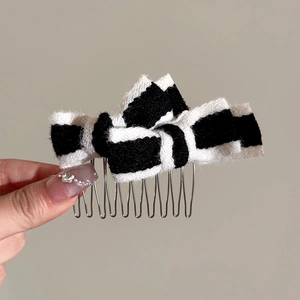 Close-up of black and white striped plush bow hair comb with metallic teeth