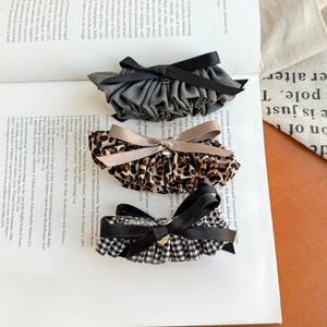 Three-piece hair bow clip set with leopard print and houndstooth patterns on vintage book