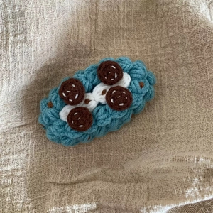 Vue détaillée de la pince à cheveux bleue tricotée main avec décors de biscuits