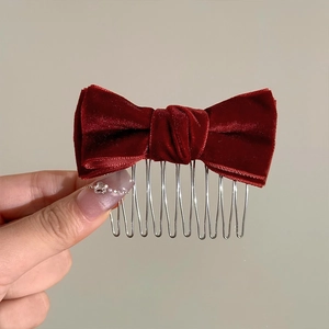 Close-up of a red velvet bow hair comb with polished silver metal teeth for styling