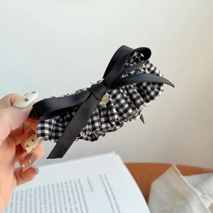 Macro detail of checkered fabric hair claw with black ribbon and silver handmade tag