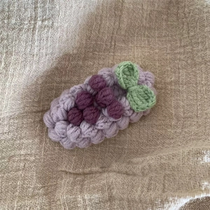 Gros plan sur une barrette à cheveux raisin au crochet fait main en fil violet et vert