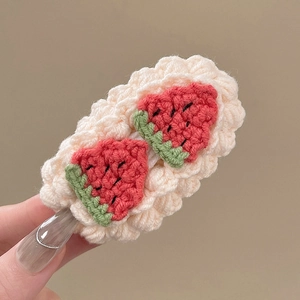 Détail d'une pince à cheveux fraise faite main au crochet avec des textures tricotées fines