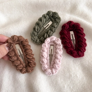 Close-up of four handmade colorful crochet hair clips in plush knit material