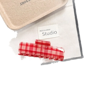 Chic red and white checkered acetate hair claw clip with a polished finish in a studio setting