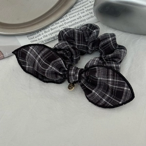 Détail d'un chouchou à nœud damier avec pendentif doré sur une page de magazine vintage