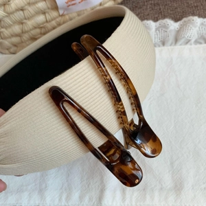 Detailed close-up of tortoise shell hair clips with non-slip teeth on beige fabric