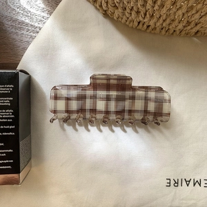 Detail view of checkered square shark hair clip in brown and white acetate finish