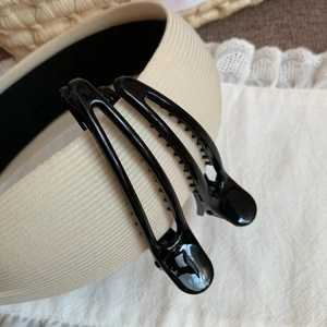 Close-up of beige ribbed fabric headband and classic glossy black duckbill hair clips