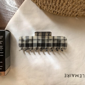 Detail showing checkered patterns on rectangular hair claw clip with smooth acrylic texture