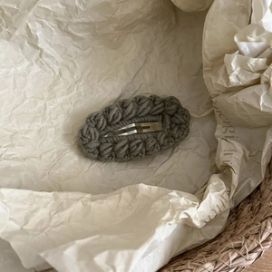 Detail of hand-knitted gray wavy edge hair clip with a minimalist forest style aesthetic