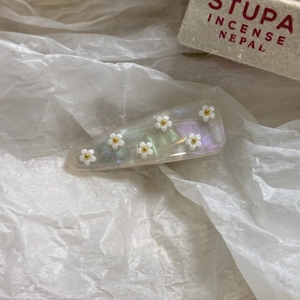 Dettaglio della clip per capelli in acetato perlato con decorazioni a fiori bianchi