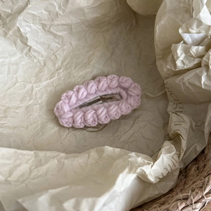 Macro shot of pink handmade crochet hair clip with soft wool texture and metallic BB base