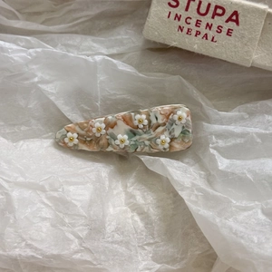 Dettaglio fermaglio in acetato con piccoli fiori bianchi 3D e centri dorati