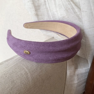 Detail of purple faux suede wide headband with a gold-tone handmade metal label