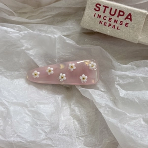 Dettaglio del fermaglio per capelli in acetato rosa con fiori 3D bianchi delicati
