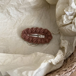 Detailed close-up of dark brown hand-knitted hair clip with silver BB metal buckle