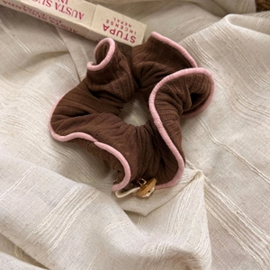 Nahaufnahme braunes Scrunchie mit rosa Rand und dekorativem Holzknopf-Detail
