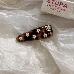 Dettaglio del fermaglio per capelli in acetato con fiori bianchi e centro dorato
