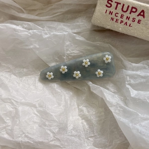 Dettaglio di un fermaglio per capelli in acetato marmorizzato blu con piccoli fiori bianchi