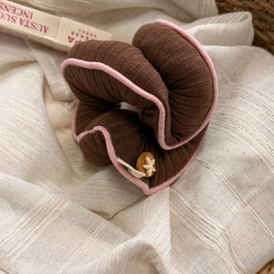 Nahaufnahme brauner Strick-Haargummi mit rosa Saum und Stern-Holzknopf-Detail