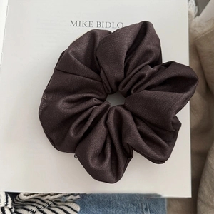 Brown fabric scrunchie with twill texture shown on a book for a minimalist chic style