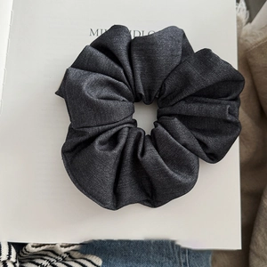 Detailed close-up of dark grey denim fabric scrunchie with soft ribbed texture