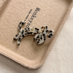 Gros plan d'une pince à cheveux chat en acétate avec motif écaille de tortue noir et blanc