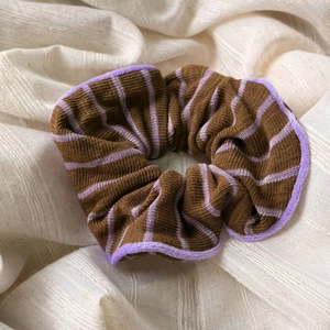 Detailed close-up of knitted scrunchie with purple stripes and soft faux fur trim