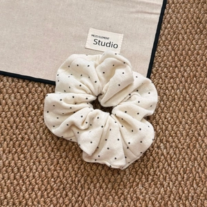 Detailed texture of a soft beige polka dot scrunchie on a woven background