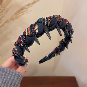Detail of navy knit headband with colorful braided ropes and inner plastic hair teeth