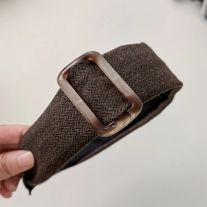 Detailed macro view of brown herringbone fabric headband with amber acrylic buckle ornament