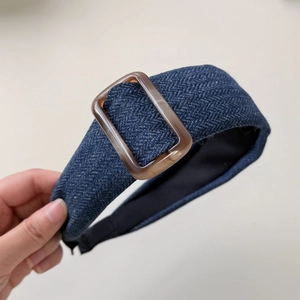 Detailed close-up of blue herringbone fabric headband with a decorative brown resin buckle