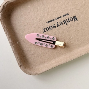 Detailed close-up of pink acetic acid floral hair clip with sparkling rhinestones and gold metal