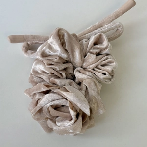 Gros plan du chouchou en velours rose champagne avec texture florale multicouche