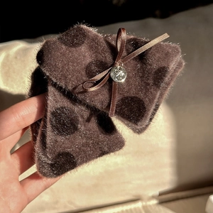 Détail de la pince à cheveux en peluche à pois marrons avec nœud en velours et pendentif argent