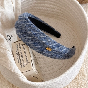 Detailed texture of blue striped wool headband with a golden Hand Made label