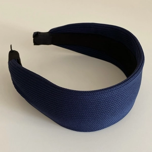 Detailed close-up of dark blue wide headband with spiral knitted texture and fabric lining